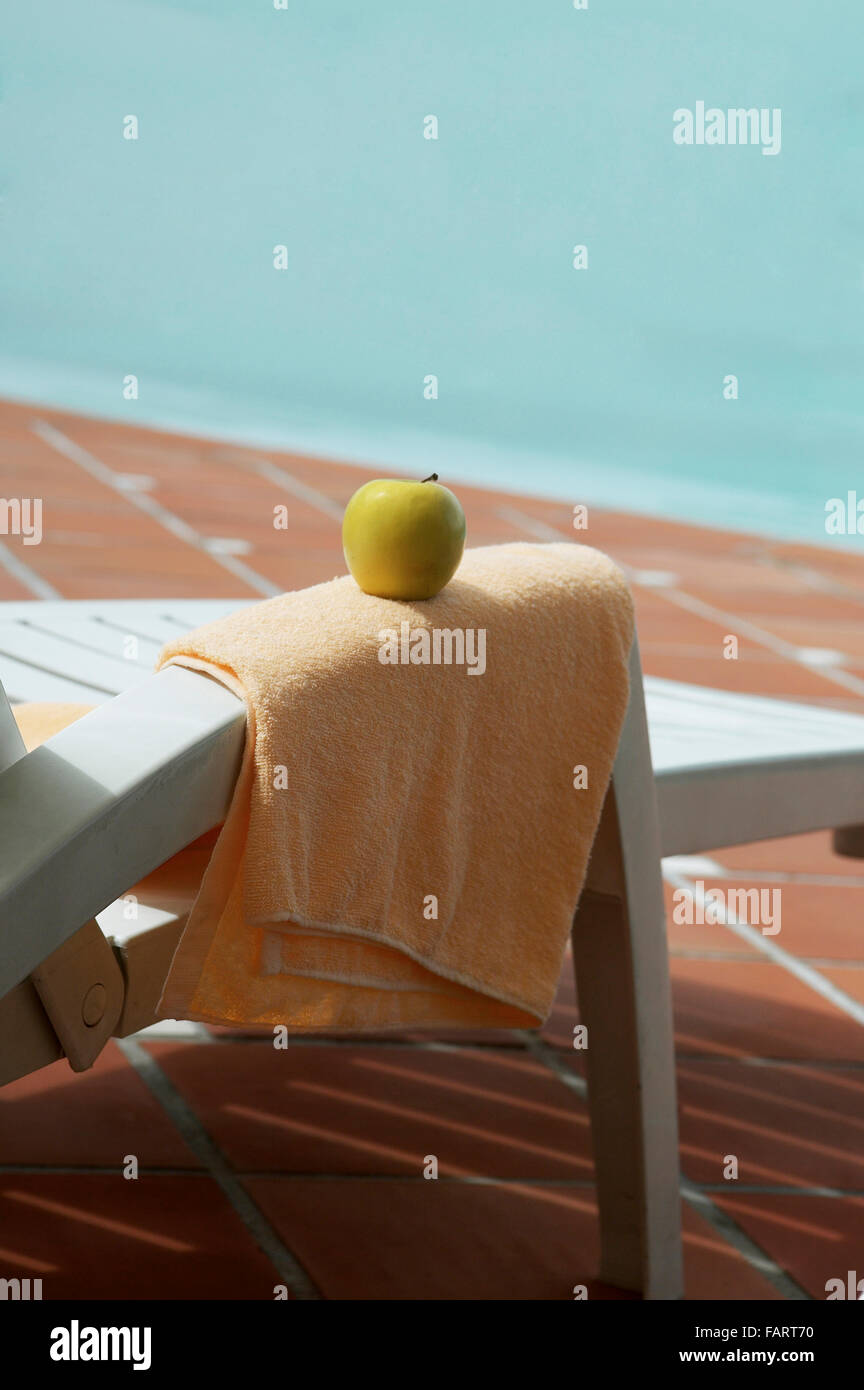 Apple e l'asciugamano sulla sede vuota per il resto vicino alla piscina. Foto Stock