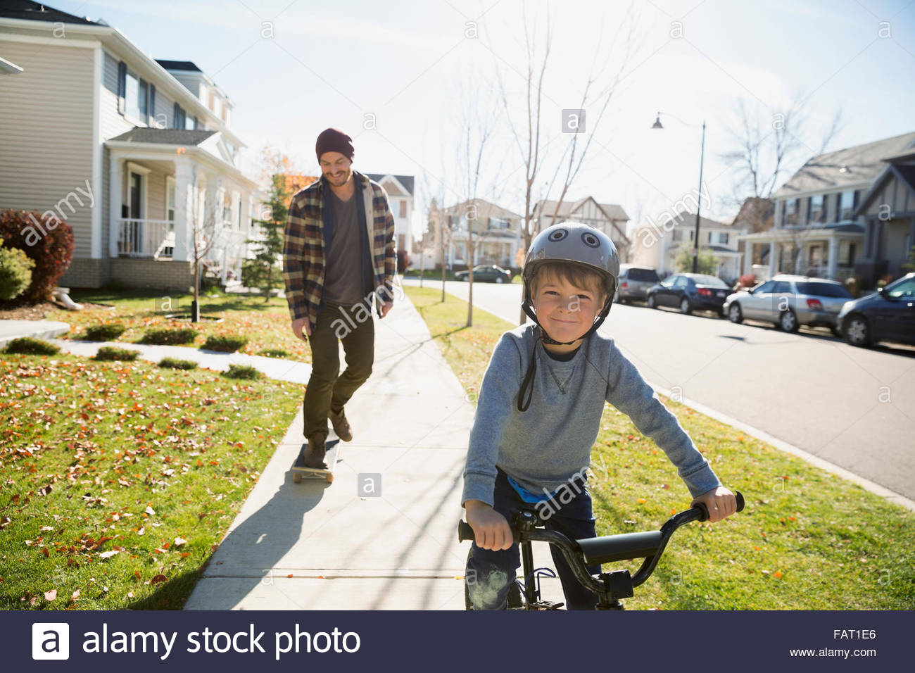 Il padre lo skateboard e figlio di equitazione quartiere bike marciapiede Foto Stock