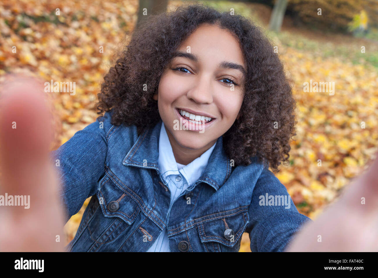 Bella felice razza mista americano africano ragazza adolescente bambino femmina sorridente con denti perfetti tenendo selfie fotografia Foto Stock