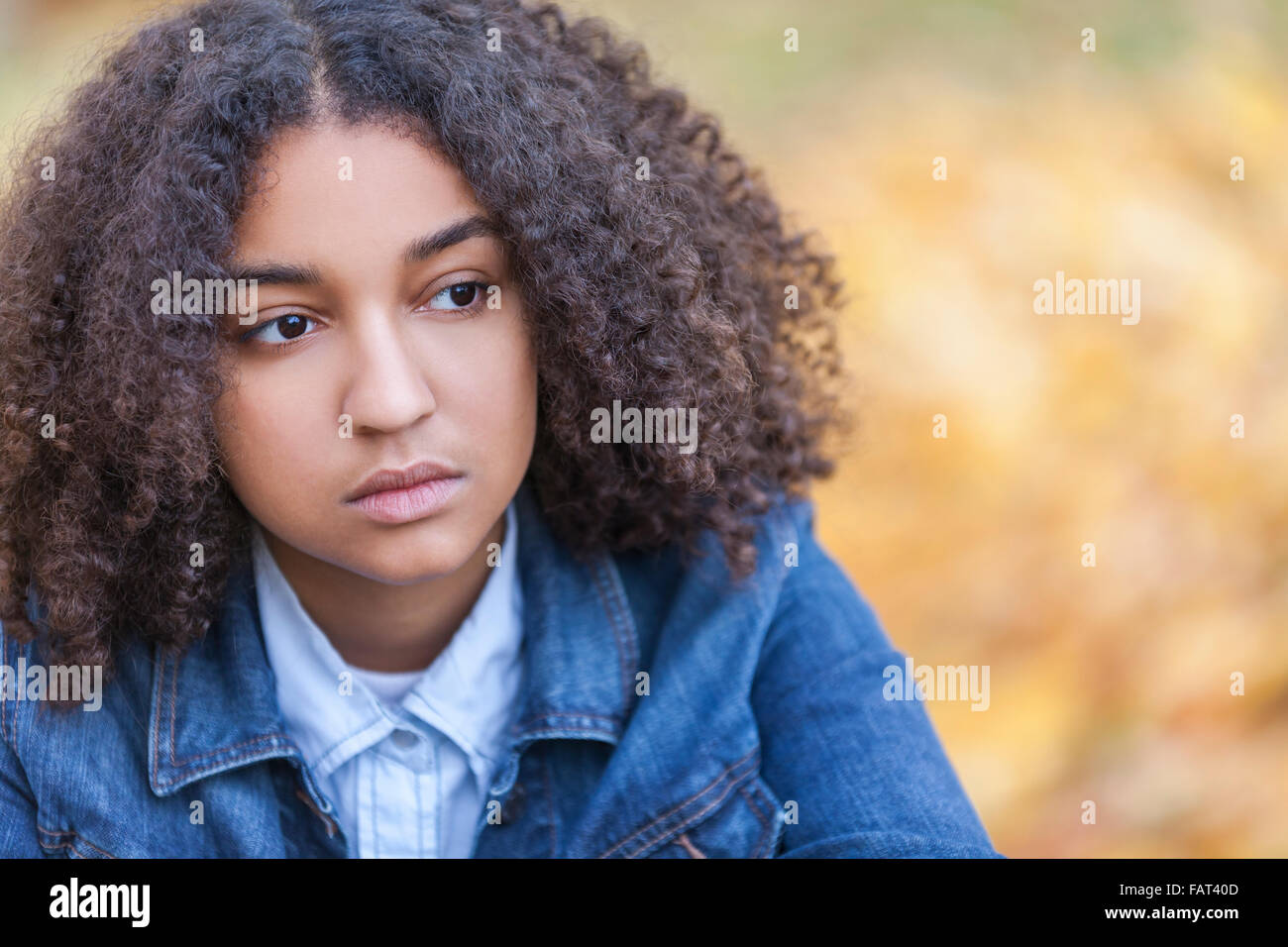 Bellissima gara di misto americano africano ragazza adolescente femmina giovane donna fuori in autunno o in autunno guardando triste premuto o se Foto Stock