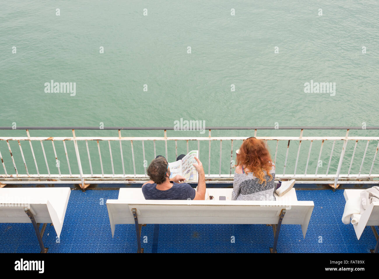 I passeggeri seduti su un sedile rilassante mentre su un traghetto tra l'Isola di Wight e la terraferma britannica Foto Stock