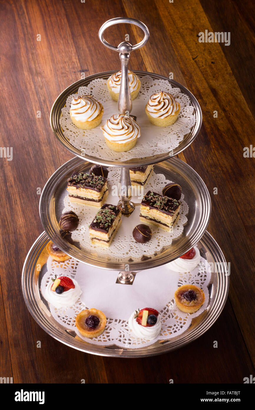 Una selezione di deliziosi dessert disposti e servita su una torta di argento stand in un inglese un high tea stile. Foto Stock