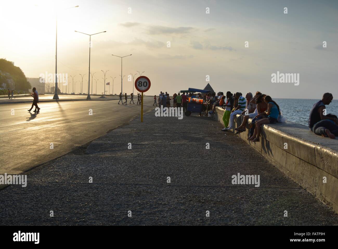 La gente del posto si riuniscono nel sole serale lungo la parete del mare di Malecon Havana Cuba Foto Stock