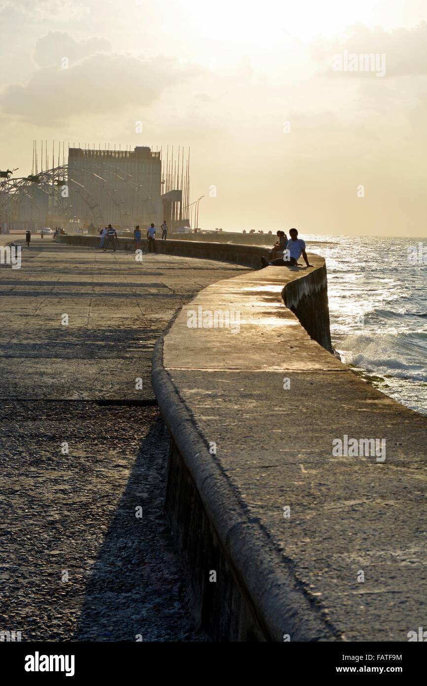La popolazione locale inizia a raccogliere la sera sun per passeggiare o sedersi sul mare parete lungo il Malecon a l'Avana Foto Stock