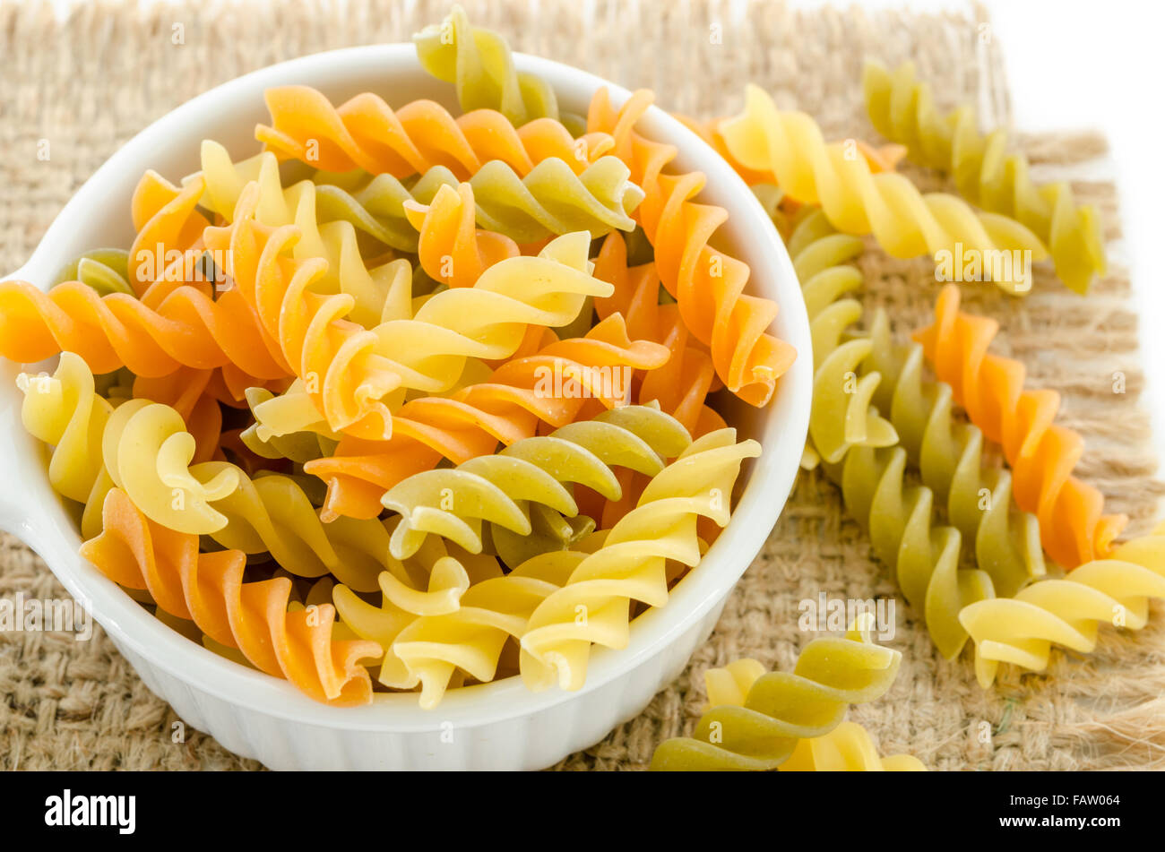 Essiccata la pasta italiana (maccheroni) nella vaschetta di colore bianco su sfondo di sacco. Foto Stock