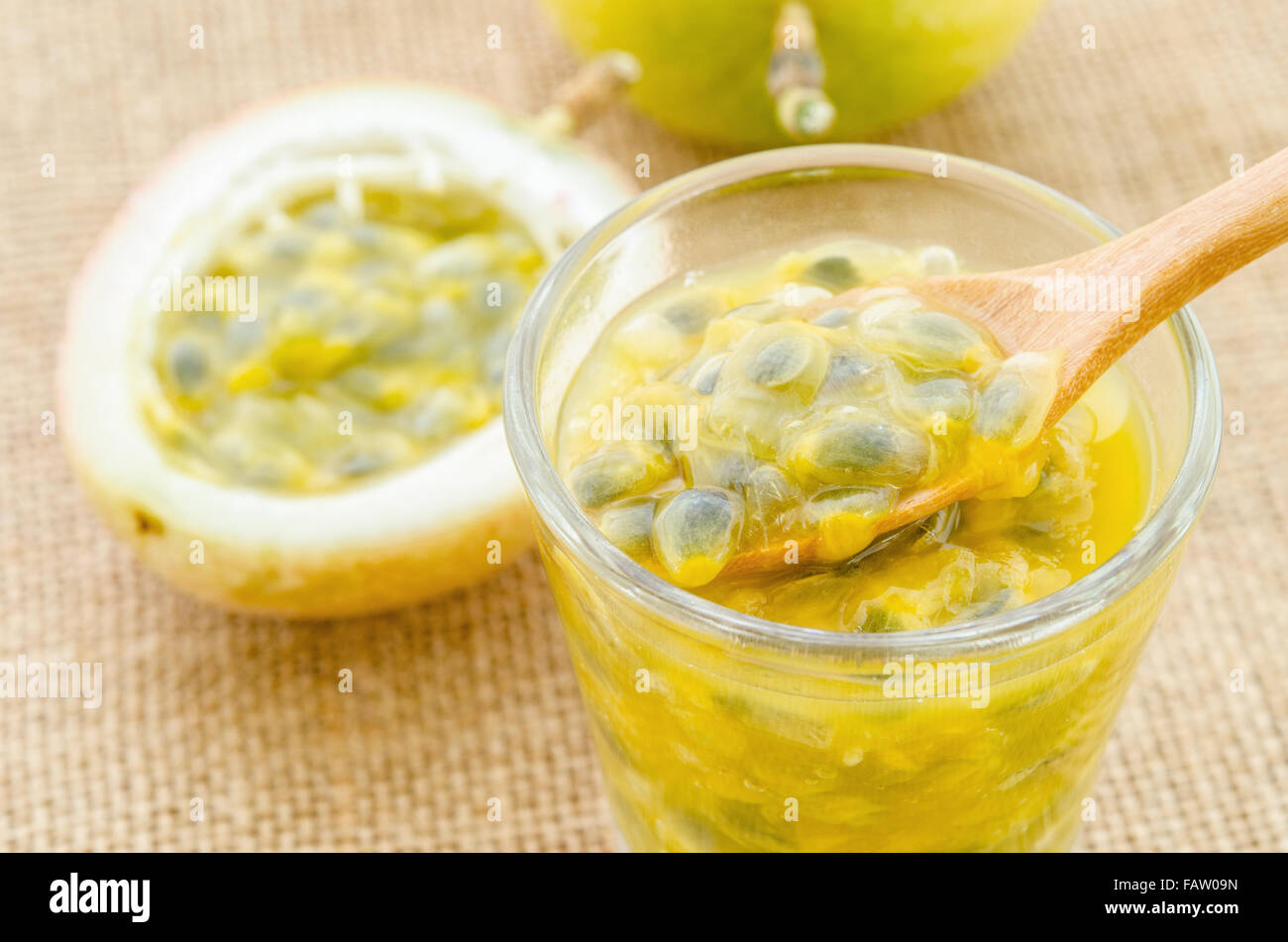 Succo di frutto della passione in vetro e freschi frutti della passione su sfondo di sacco. Foto Stock