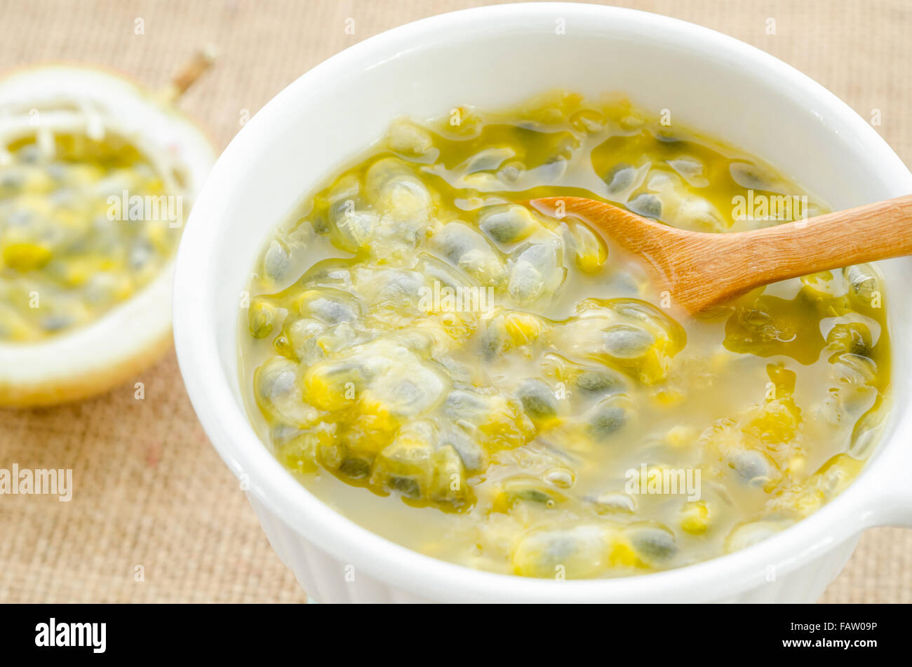 Succo di frutto della passione white ciotola con il cucchiaio di legno sul sacco sfondo. Foto Stock
