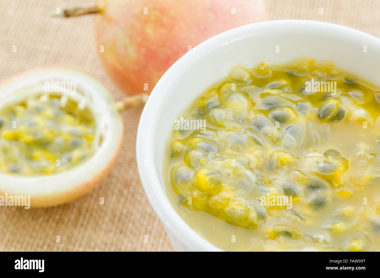 Succo di frutto della passione ciotola bianco su sfondo di sacco. Foto Stock