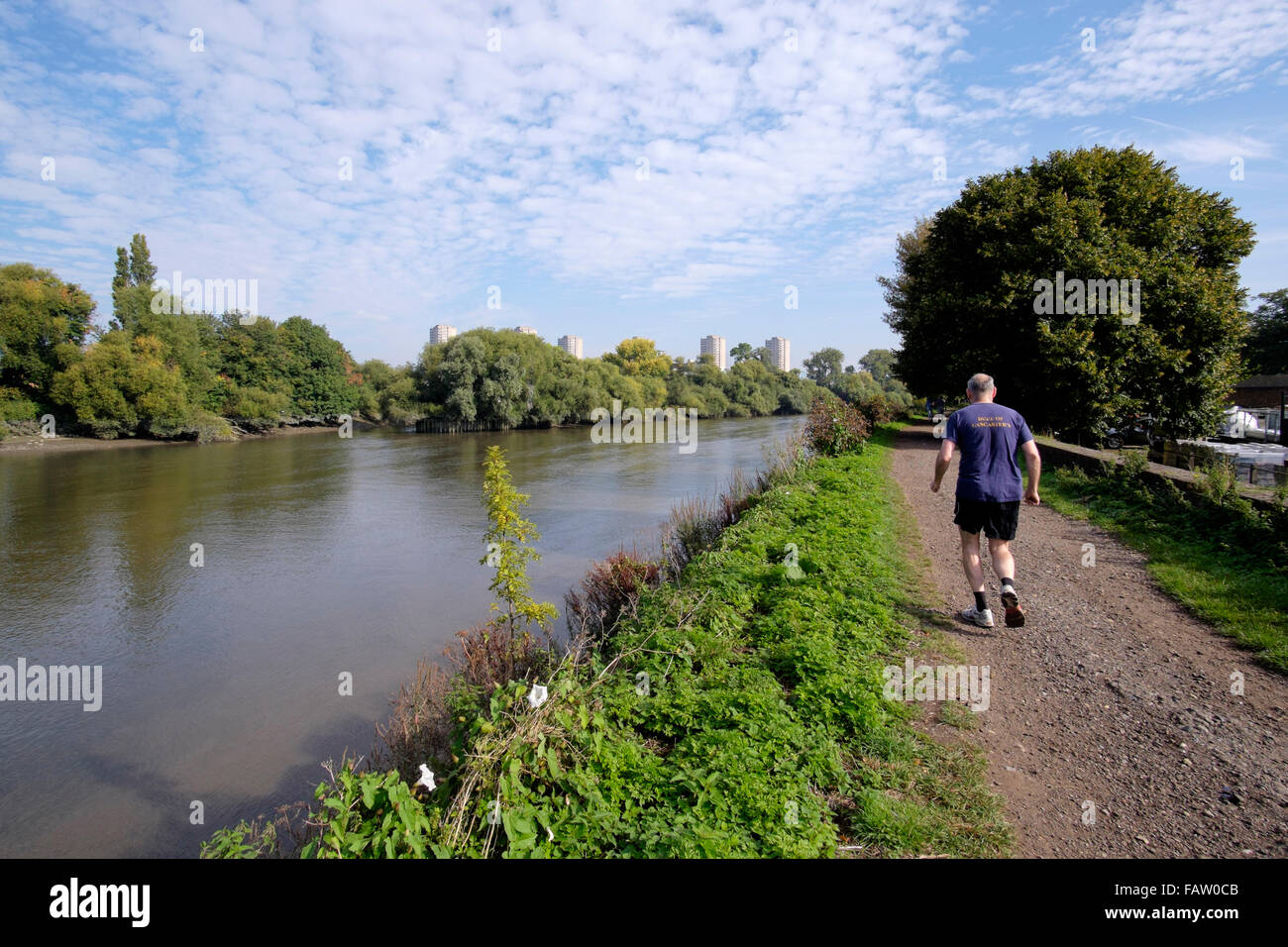 Un anziano uomo corre lungo la strada alzaia verso Kew Bridge sul fiume Tamigi, London, England, Regno Unito Foto Stock