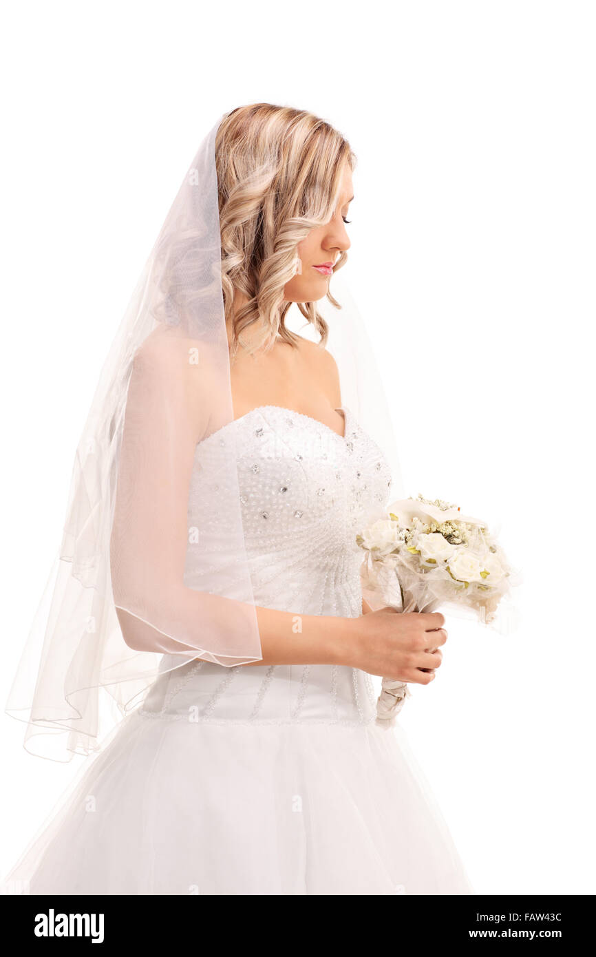 Colpo verticale di un preoccupato giovane sposa a piedi con un matrimonio fiore e guardando verso il basso isolati su sfondo bianco Foto Stock