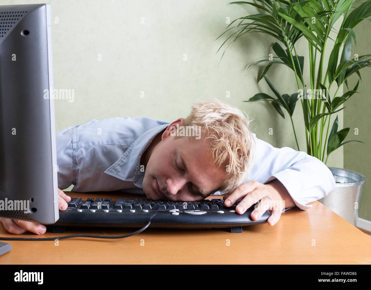 Stanco uomo addormentato crollati sulla tastiera del computer quando si lavora in ufficio Modello di Rilascio: Sì. Proprietà di rilascio: No. Foto Stock