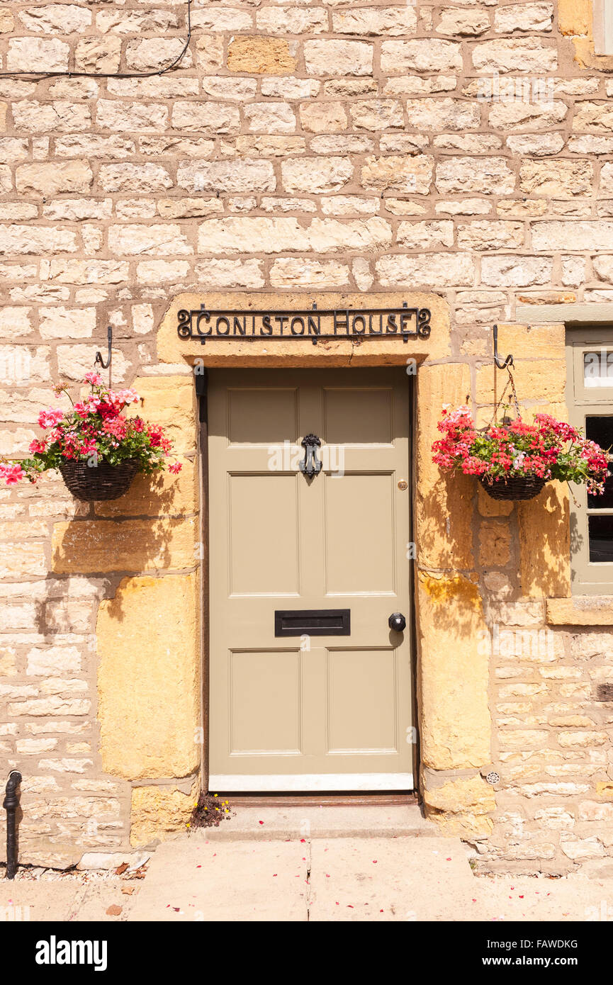 Una bella porta anteriore con cestelli appesi a Stow-su-il-Wold , Cheltenham, Gloucestershire , Inghilterra , Inghilterra , Regno Unito Foto Stock
