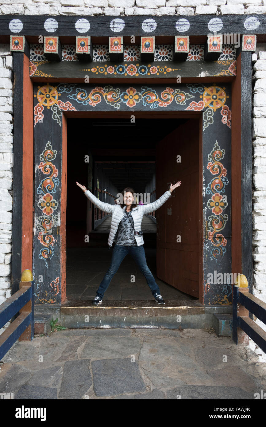 Una donna si trova in un portale ornato, Rinpung Dzong; Paro, Bhutan Foto Stock