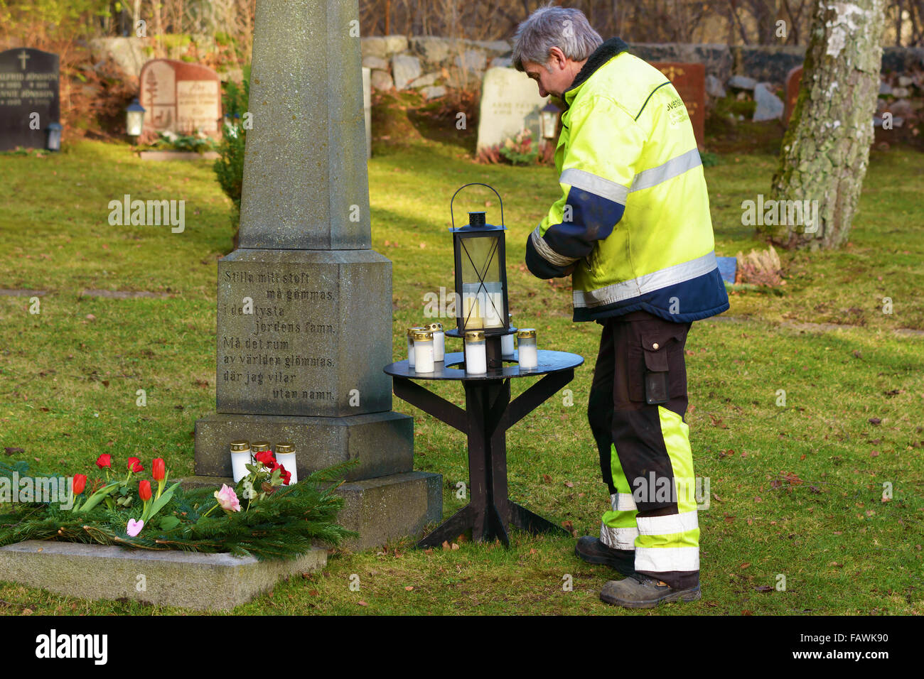 Ronneby, Svezia - 29 dicembre 2015: Sconosciuto cimitero maschio lavoratore in piedi accanto alla lapide commemorativa di persone senza nome. Sm Foto Stock