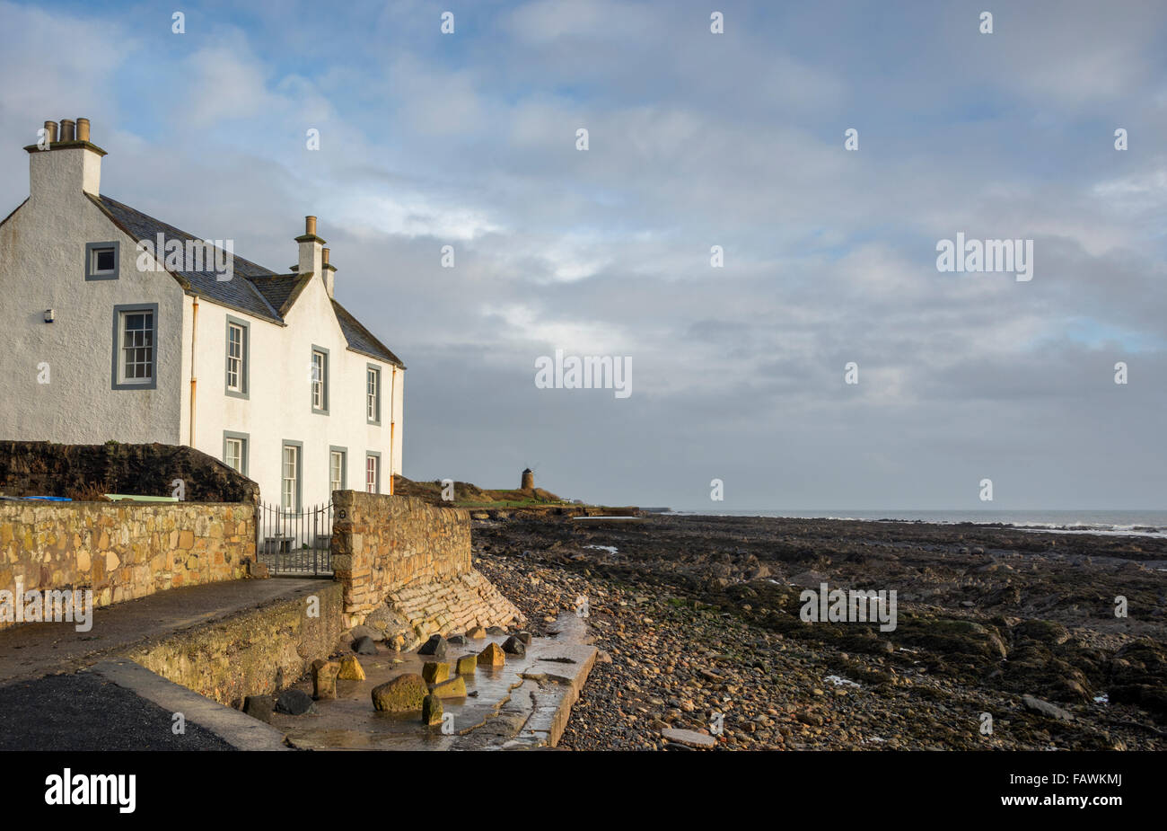 Vista costiera dal villaggio di St Monan con il suo mulino a vento a distanza e un cottage in primo piano, Fife, Scozia. Foto Stock