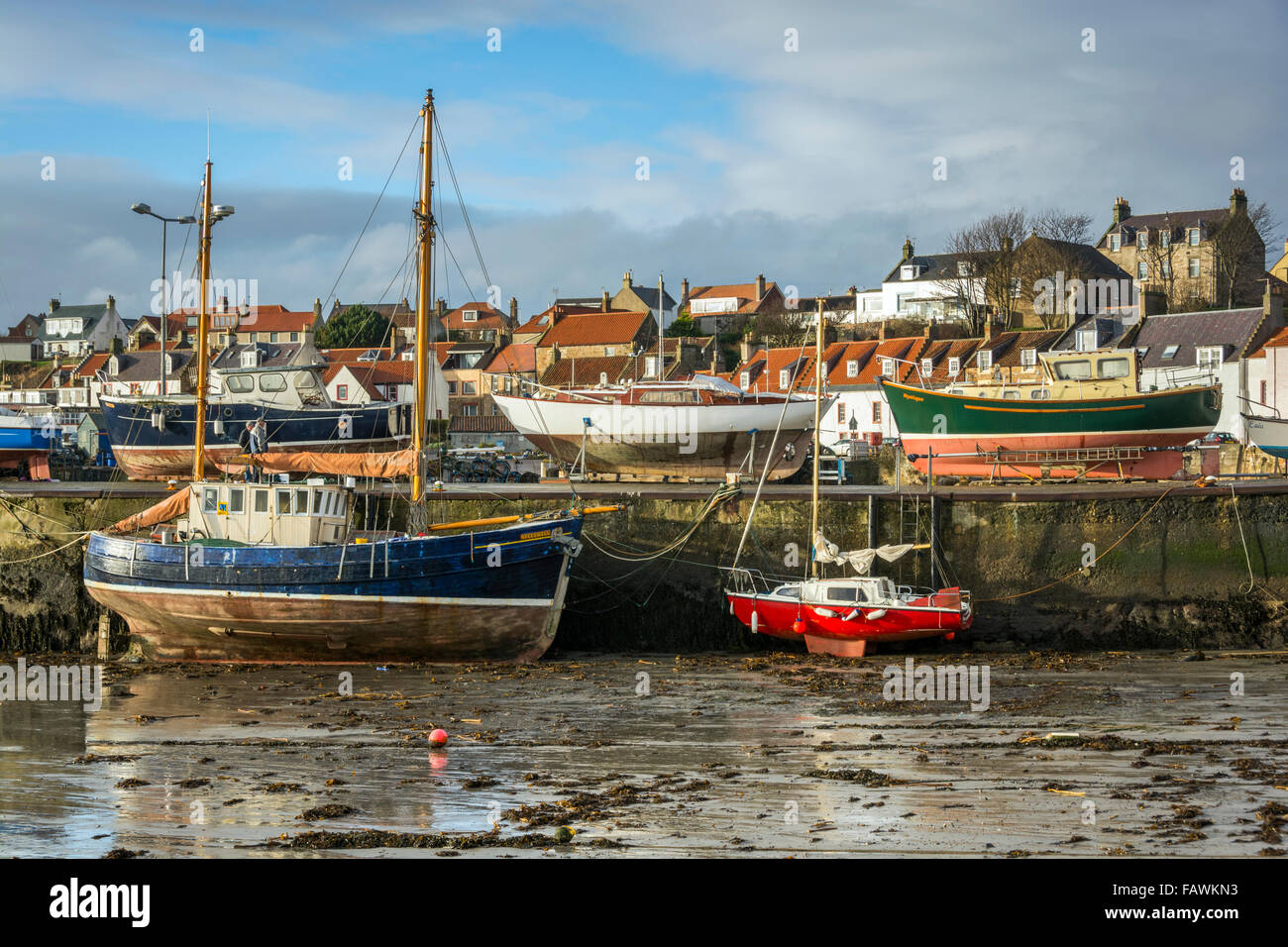Barche ormeggiate contro la parete del porto del villaggio di pescatori di St Monan sulla costa di Fife in Scozia. Foto Stock