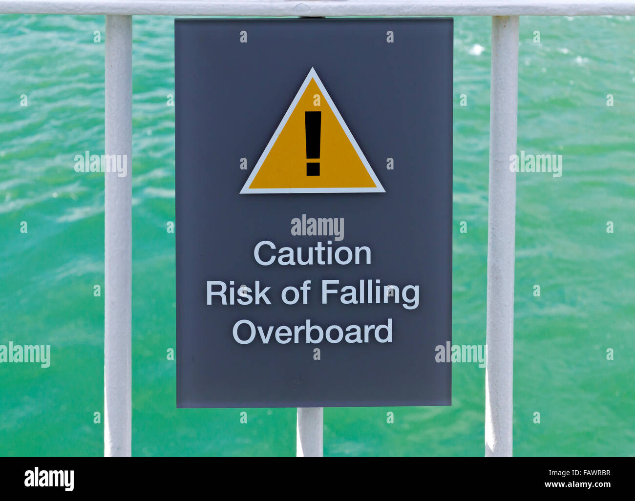 Attenzione al rischio di caduta in mare un cartello di segnalazione di pericolo giallo triangolo e un punto esclamativo su una nave passeggeri in mare Foto Stock