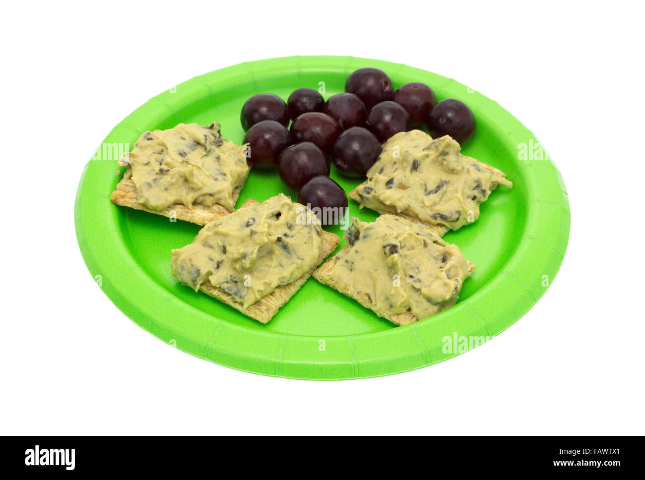 Un pasto di dieta di parecchi spinaci hommus sul grano intero crackers con uve su un verde piatto di carta Foto Stock