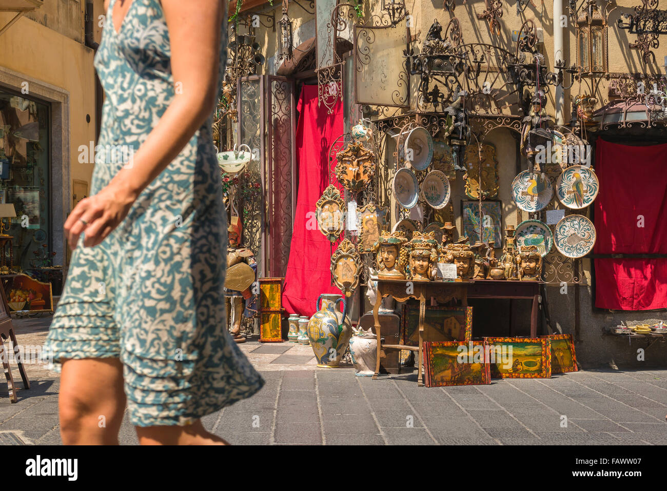 Taormina shopping, un turista passa ceramiche e vasi per la vendita sul display al di fuori di un negozio di antiquariato nel corso Umberto I,Taormina. Foto Stock