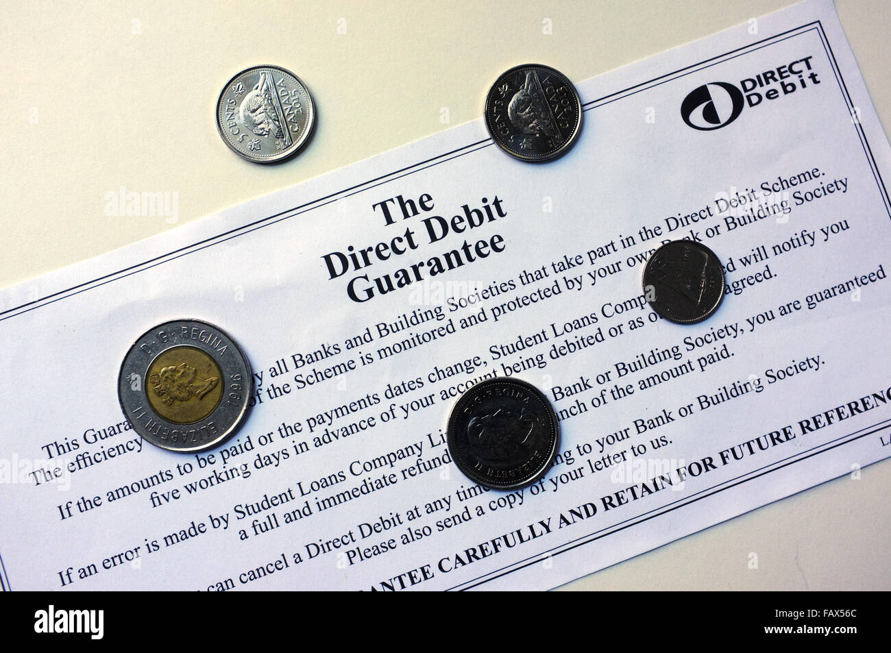L'addebito garanzia con monete sulla sommità di esso fotografati contro uno sfondo bianco. Foto Stock