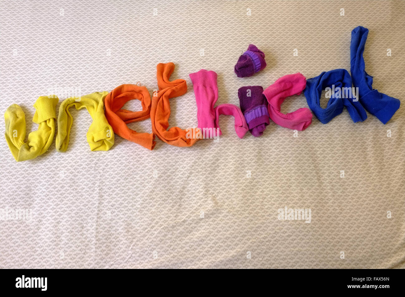 La parola immorale fatta di calze colorate posa su un piumone. Foto Stock