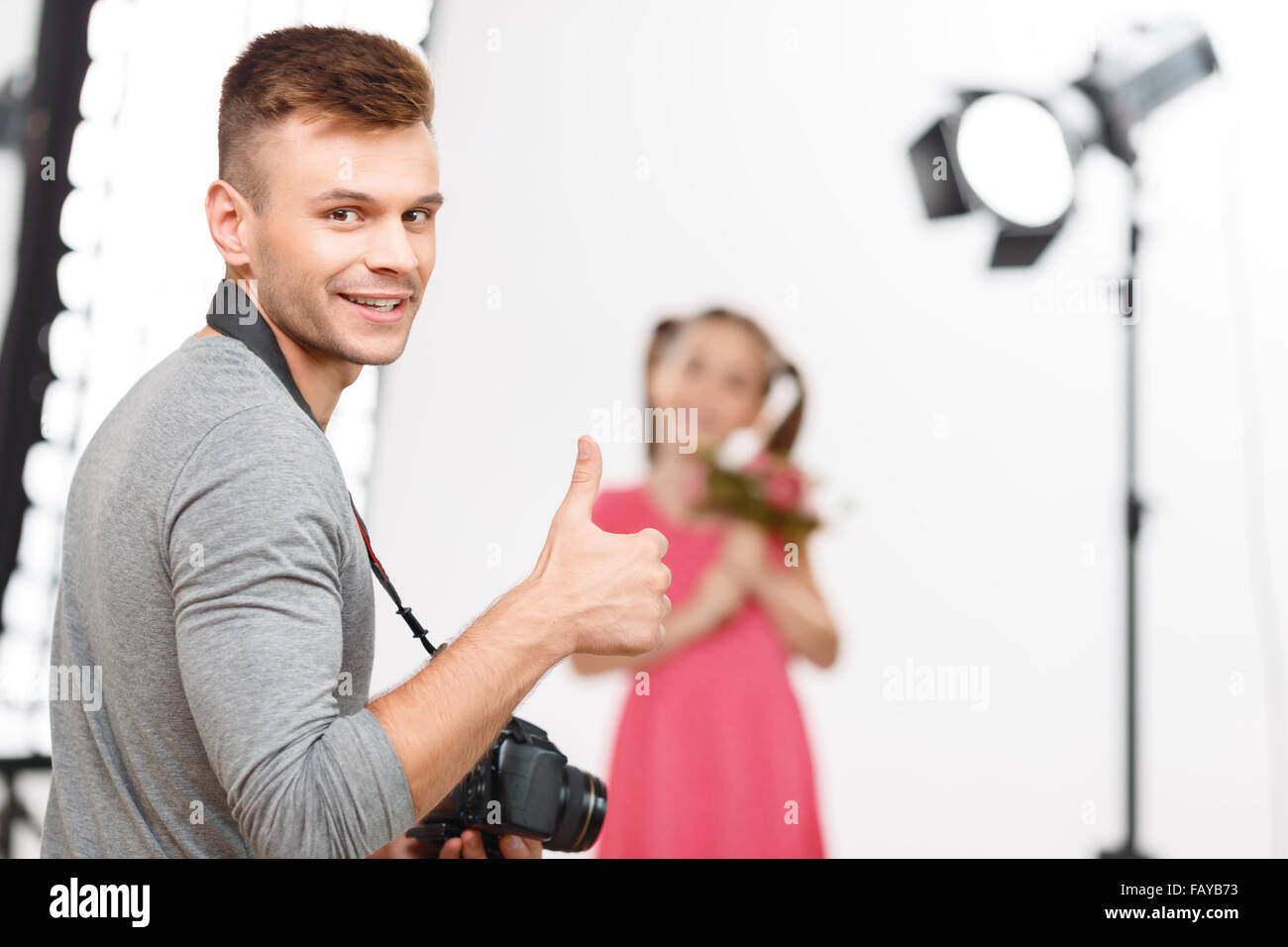 Giovane maschio fotografo mostra Thumbs up prima di scattare le foto. Foto Stock