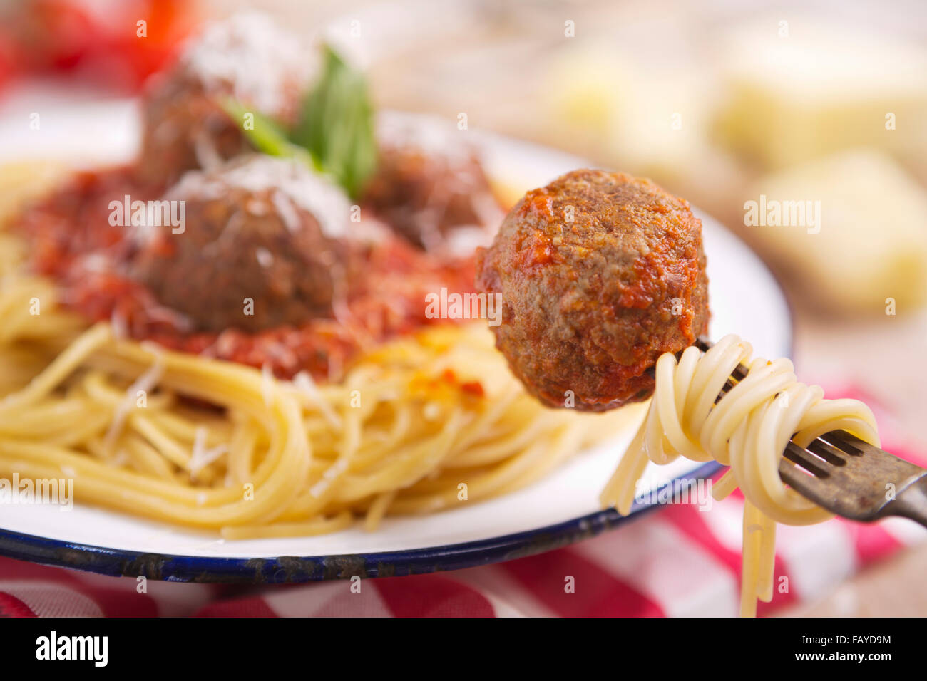 Un piatto di spaghetti con le polpette di carne, guarnita con un po' di parmigiano grattugiato e basilico. Una polpetta è prelevato con una forchetta. Foto Stock