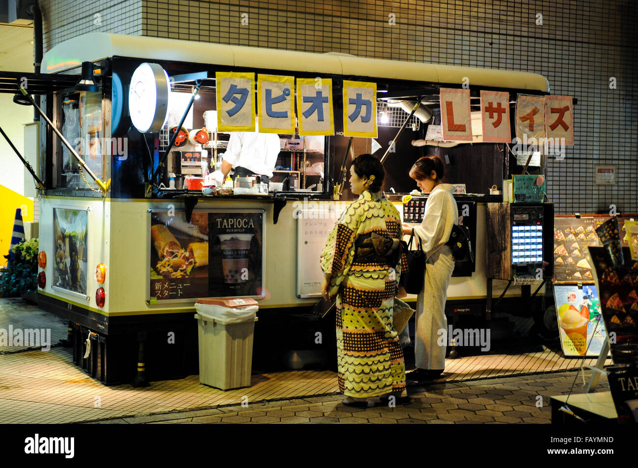 Due donne giapponesi l'acquisto di cibo di strada di indossare il kimono in Asakusa Tokyo Giappone Foto Stock