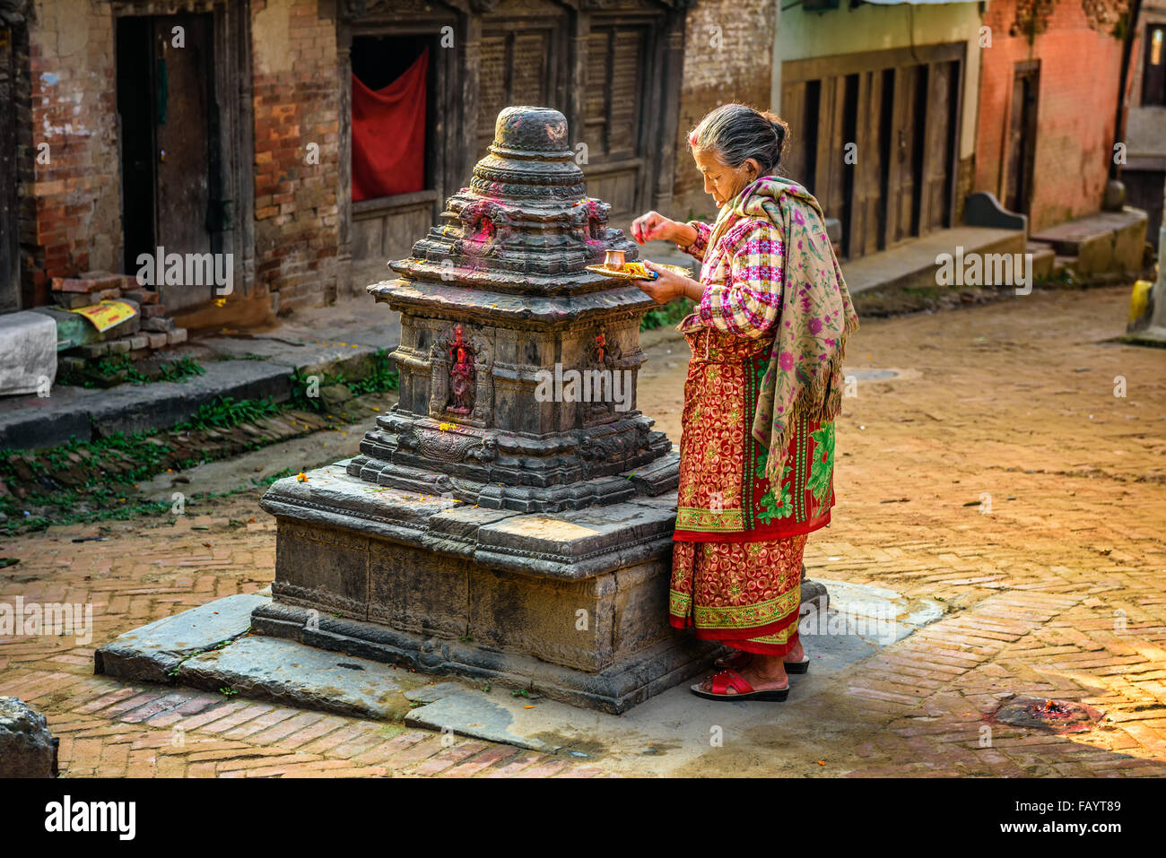 Vecchia donna accendere una candela prima di preghiera in strada di Kathmandu Foto Stock
