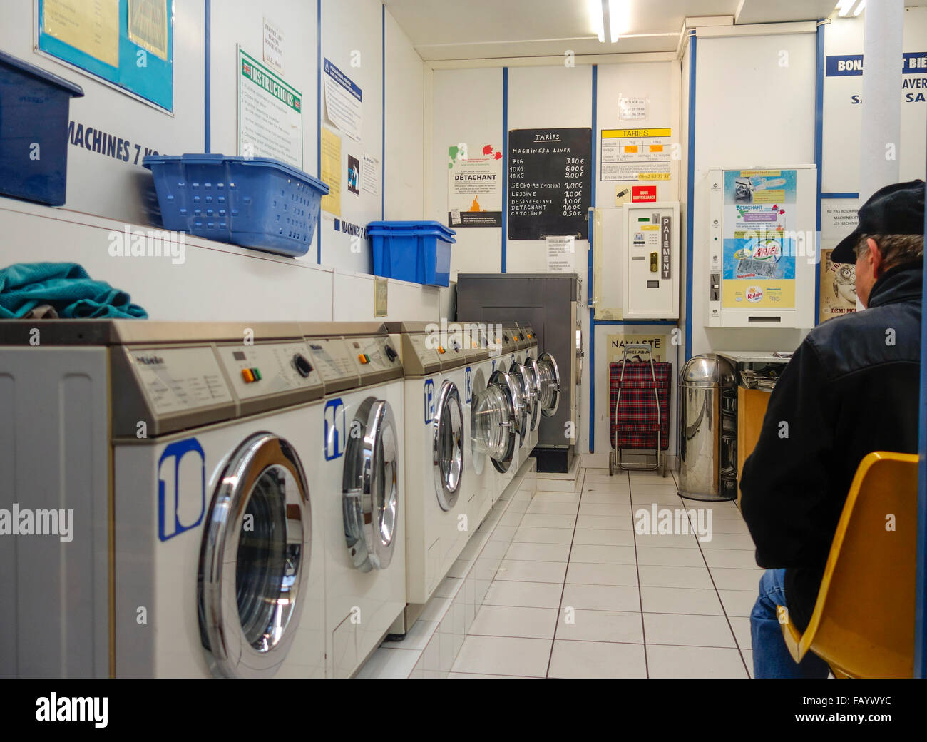 Uomo in attesa per il lavaggio in lavanderie a gettoni. Foto Stock
