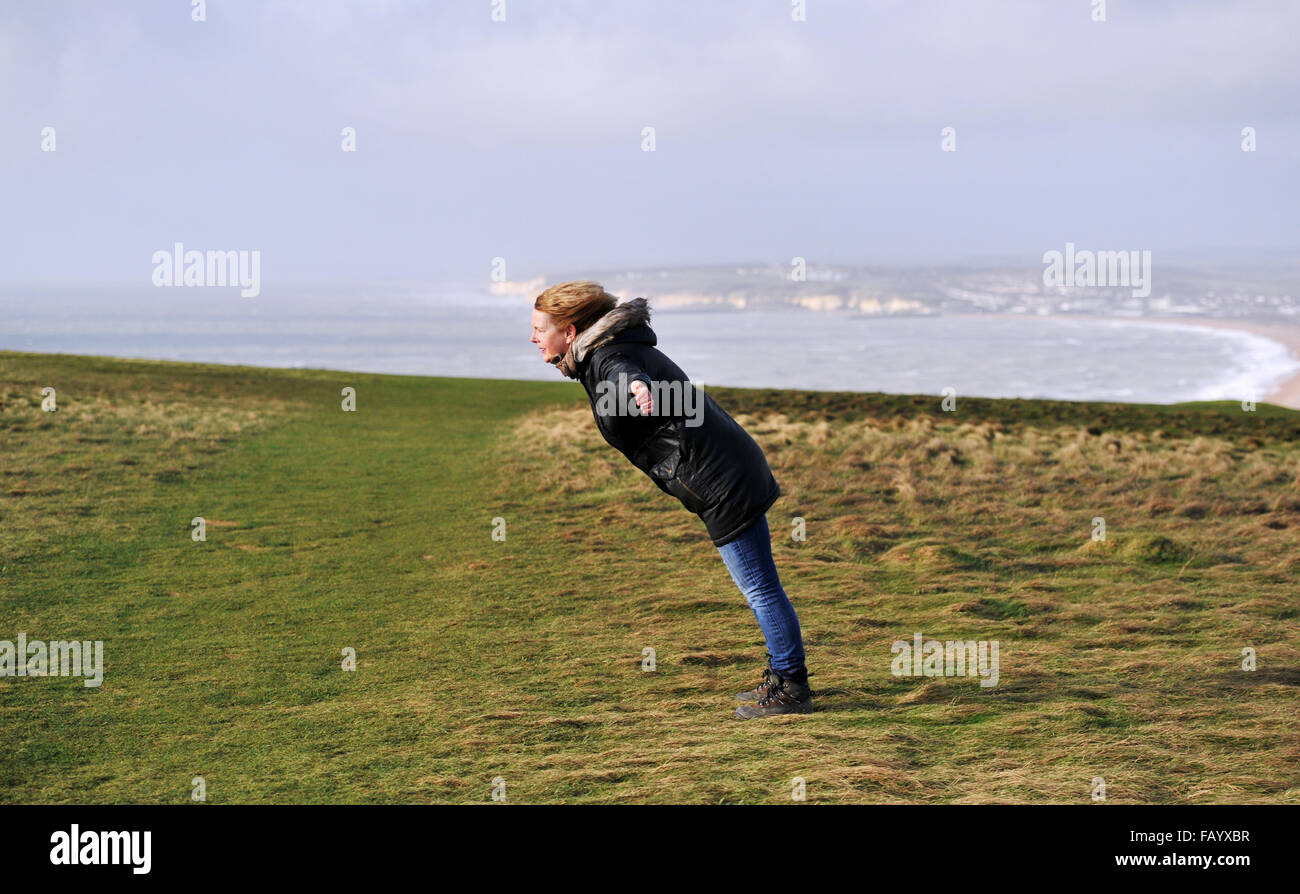 La donna fatica a stare in piedi in venti alti sulla parte superiore della testa di Seaford scogliere in East Sussex parte del South Downs Way Foto Stock