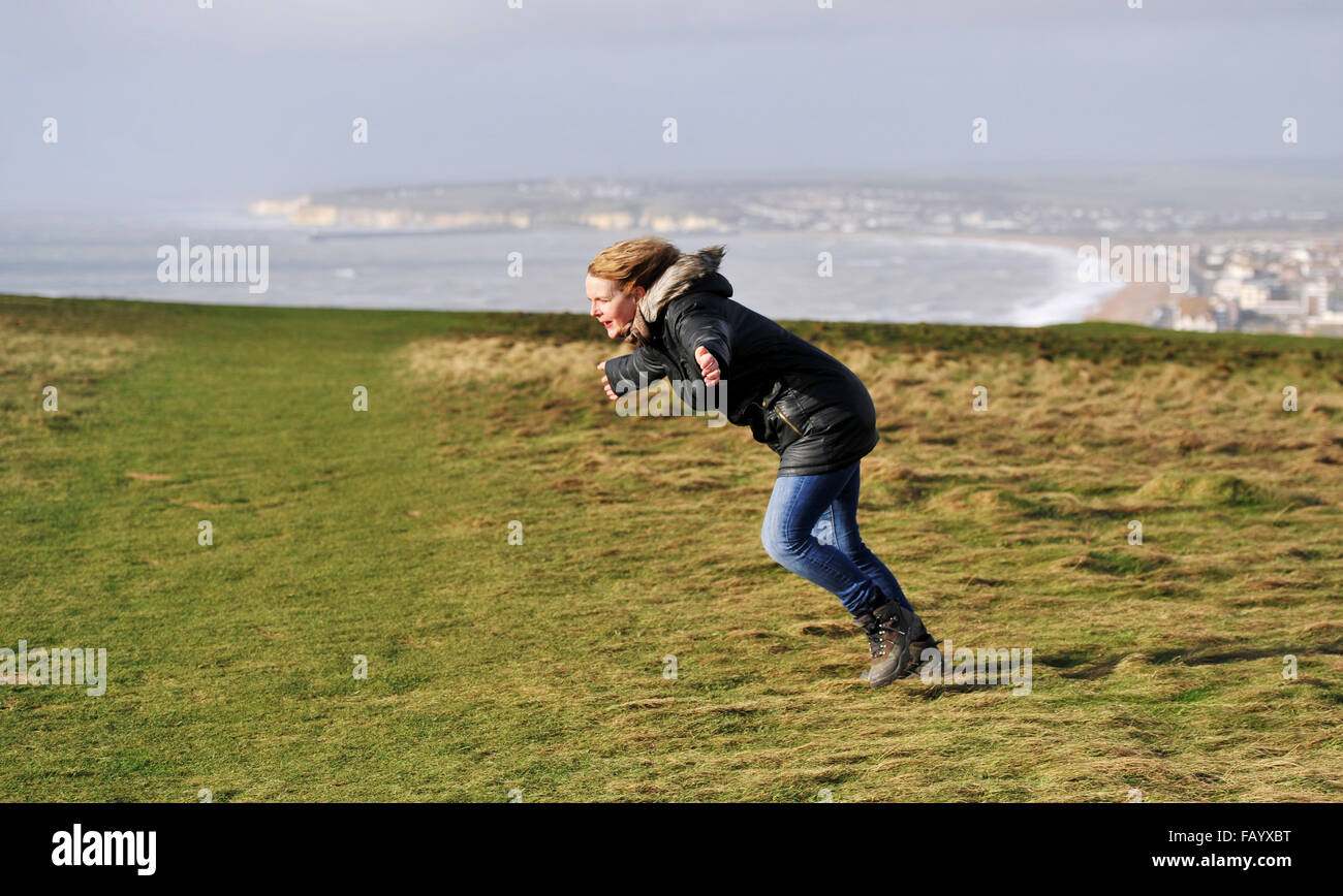 La donna fatica a stare in piedi in venti alti sulla parte superiore della testa di Seaford scogliere in East Sussex parte del South Downs Way Foto Stock