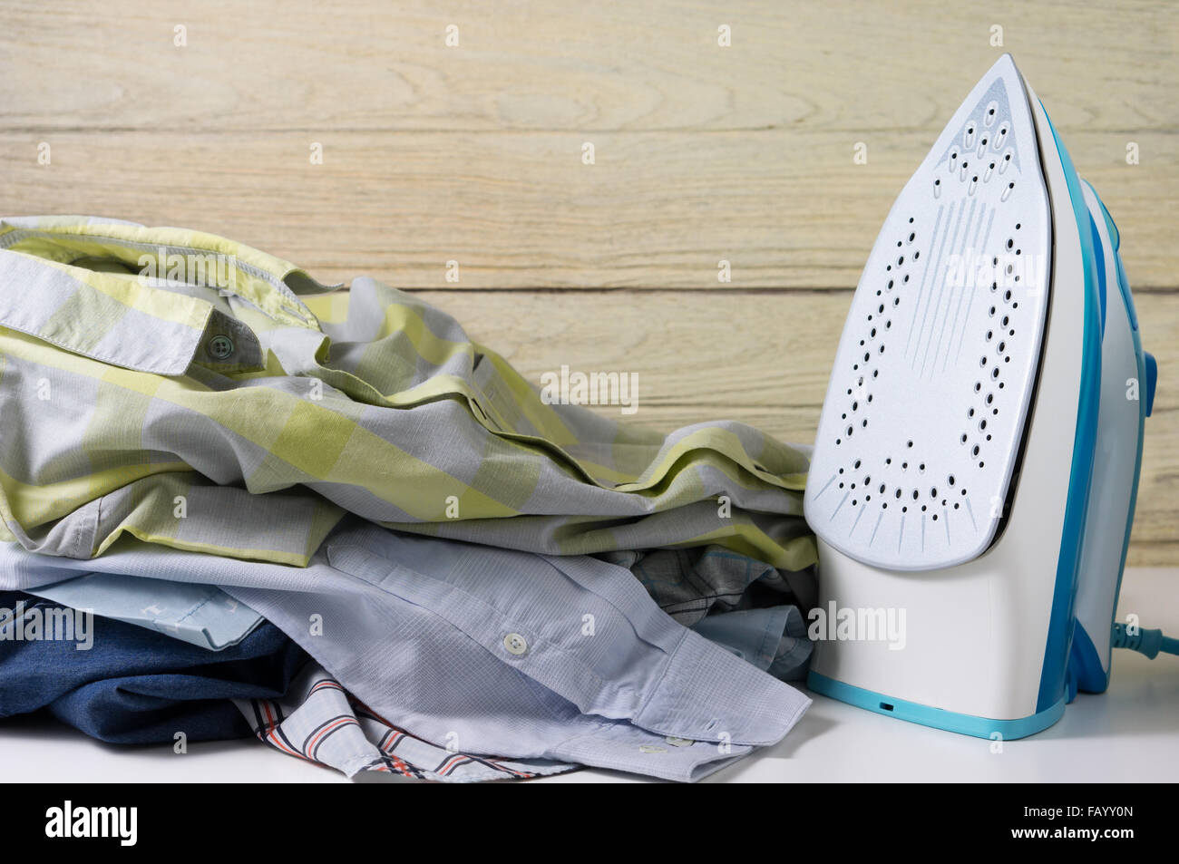 Servizio lavanderia faccende di casa con la pila di camicie e ferro da stiro elettrico Foto Stock