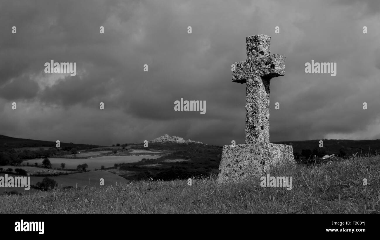 Una croce di pietra nel sagrato della chiesa di San Pancrazio chiesa in Widecombe-nel-Moor, Devon, con rocce Bonehill nella distanza Foto Stock