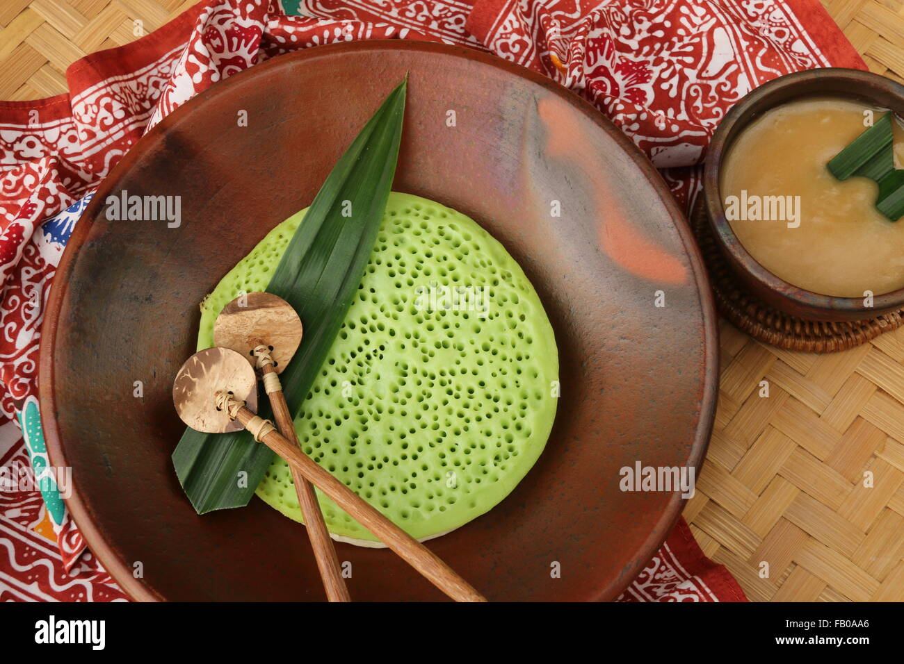 Durian Serabi, latte di cocco pancake serviti con palm salsa di zucchero con aggiunta di durian. Placcato su stoviglie di terracotta. Foto Stock