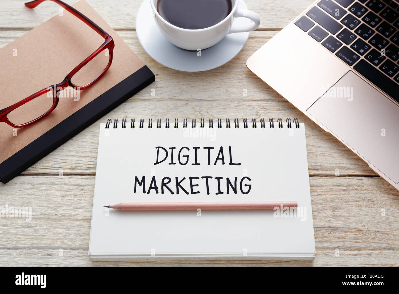 Marketing digitale nota della scrittura con il computer portatile, matita su notebook, occhiali e la tazza di caffè sulla scrivania Foto Stock