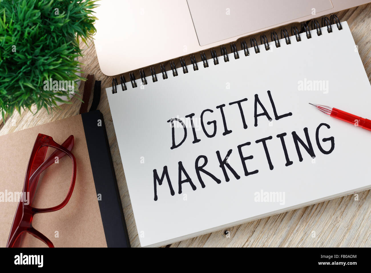 Marketing digitale nota della grafia con notebook e penna rossa sulla scrivania in ufficio Foto Stock