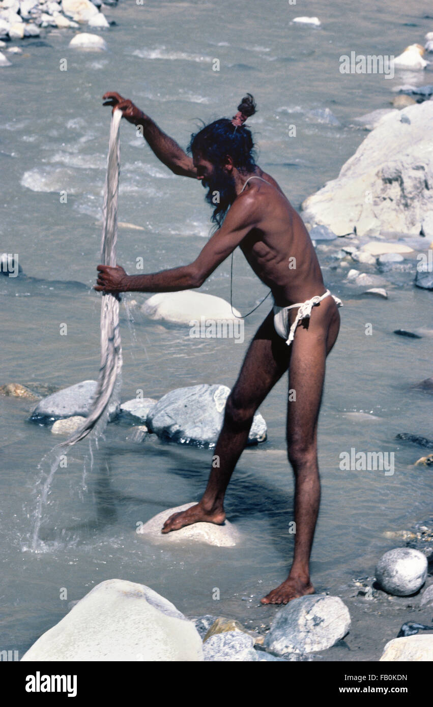 Sadhu indù o indiani uomo santo lombo di lavaggio tessuto a Gaumukh presso la sorgente del fiume santo Ganges, Gangotri, India Foto Stock