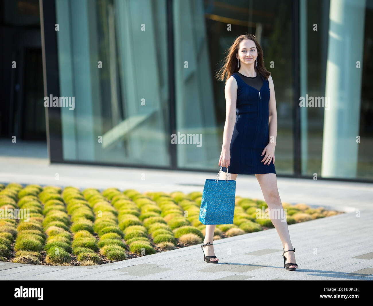 Moda ragazza con sacchetto in mano sulla strada. Foto Stock