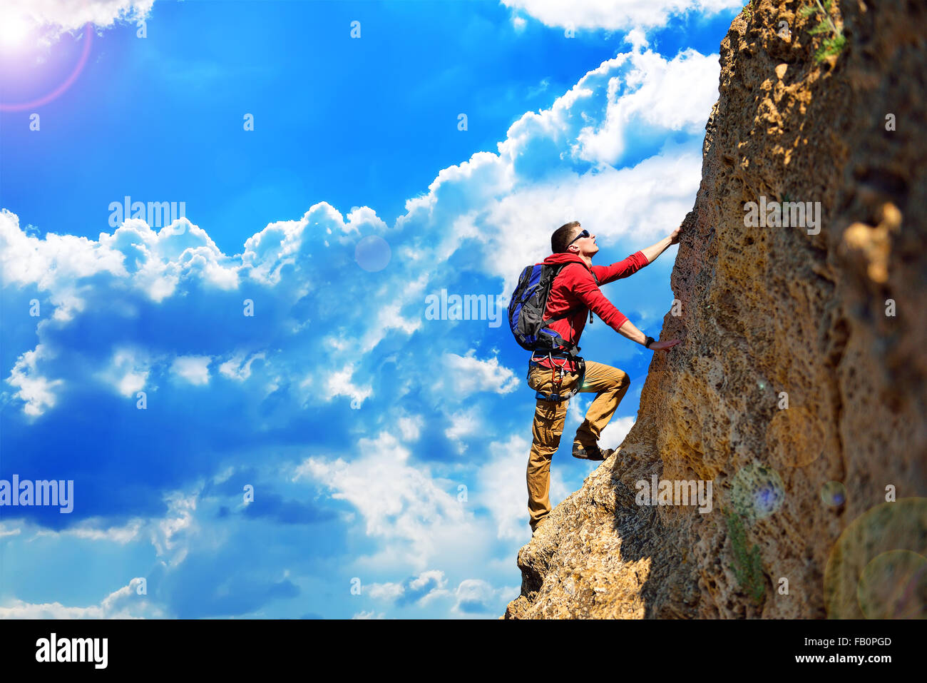 Scalatore con zaino appeso sulla roccia Foto Stock