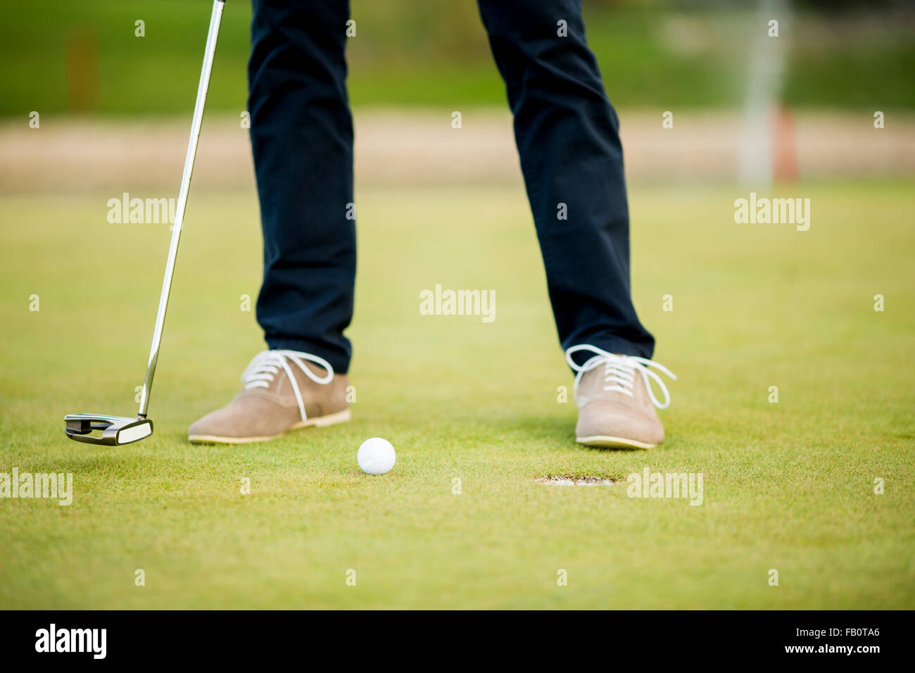 Pallina da golf, putter e ragazzo per le gambe su verde Foto Stock