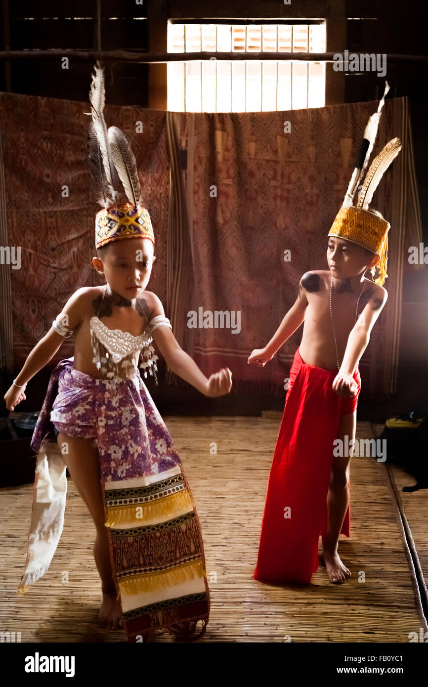 Bambini in abbigliamento tradizionale che si esibiscono danze di benvenuto durante un evento ecoturismo a Sungai Utik longhouse, Kapuas Hulu, West Kalimantan, Indonesia. Foto Stock