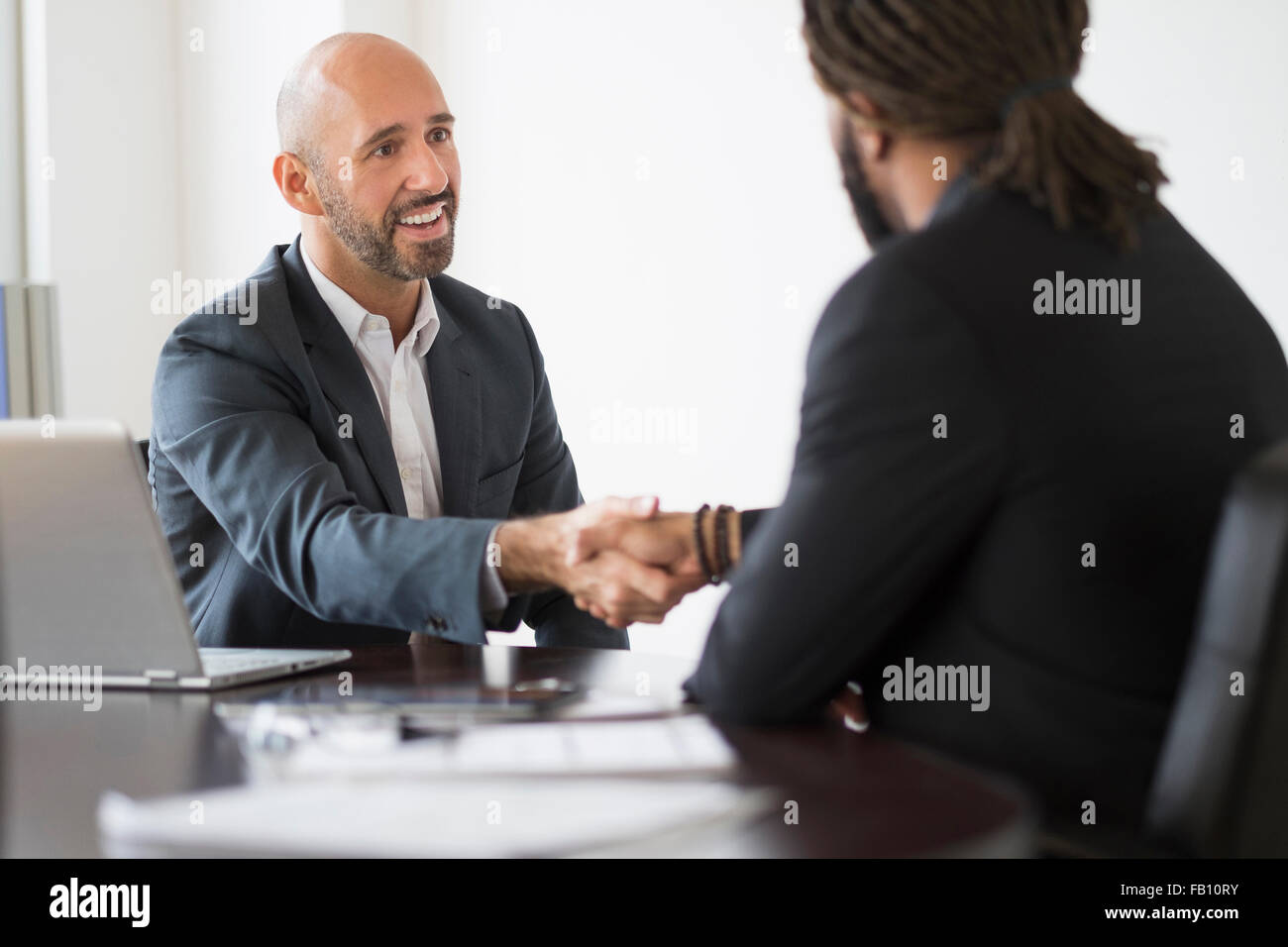 Imprenditori sorridente stringono le mani in office Foto Stock