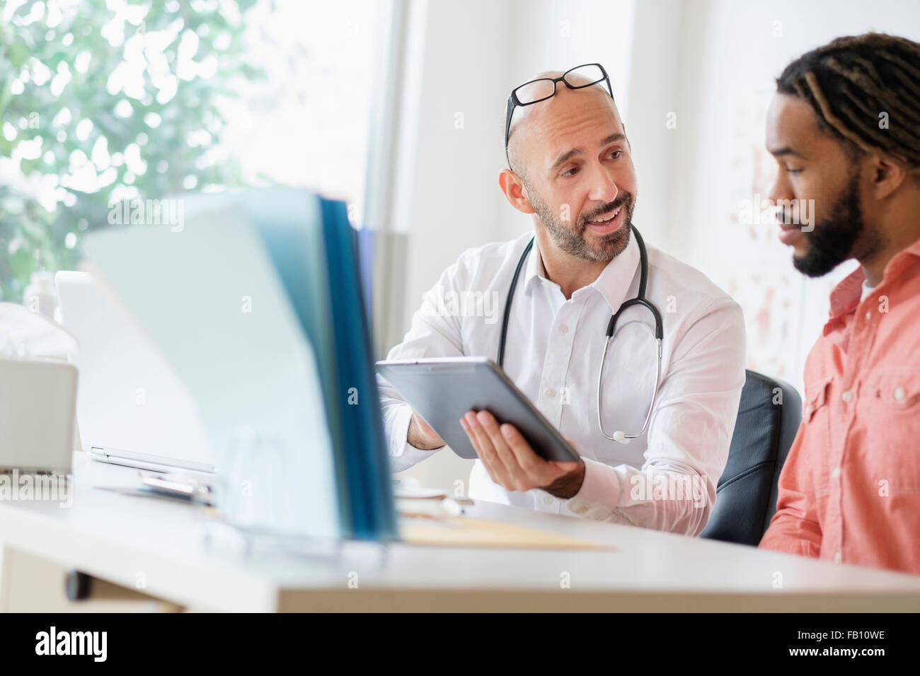 Medico dando la consultazione al paziente utilizzando tavoletta digitale Foto Stock