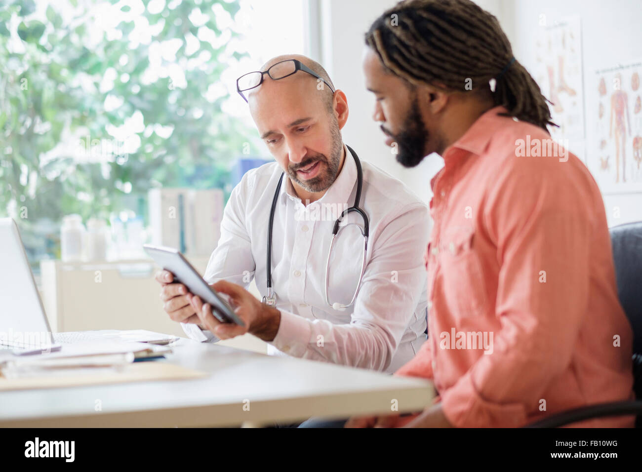 Medico dando la consultazione al paziente utilizzando tavoletta digitale Foto Stock