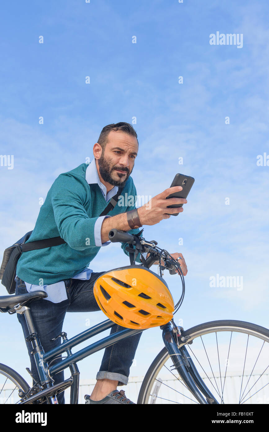 Uomo con moto usando il telefono Foto Stock