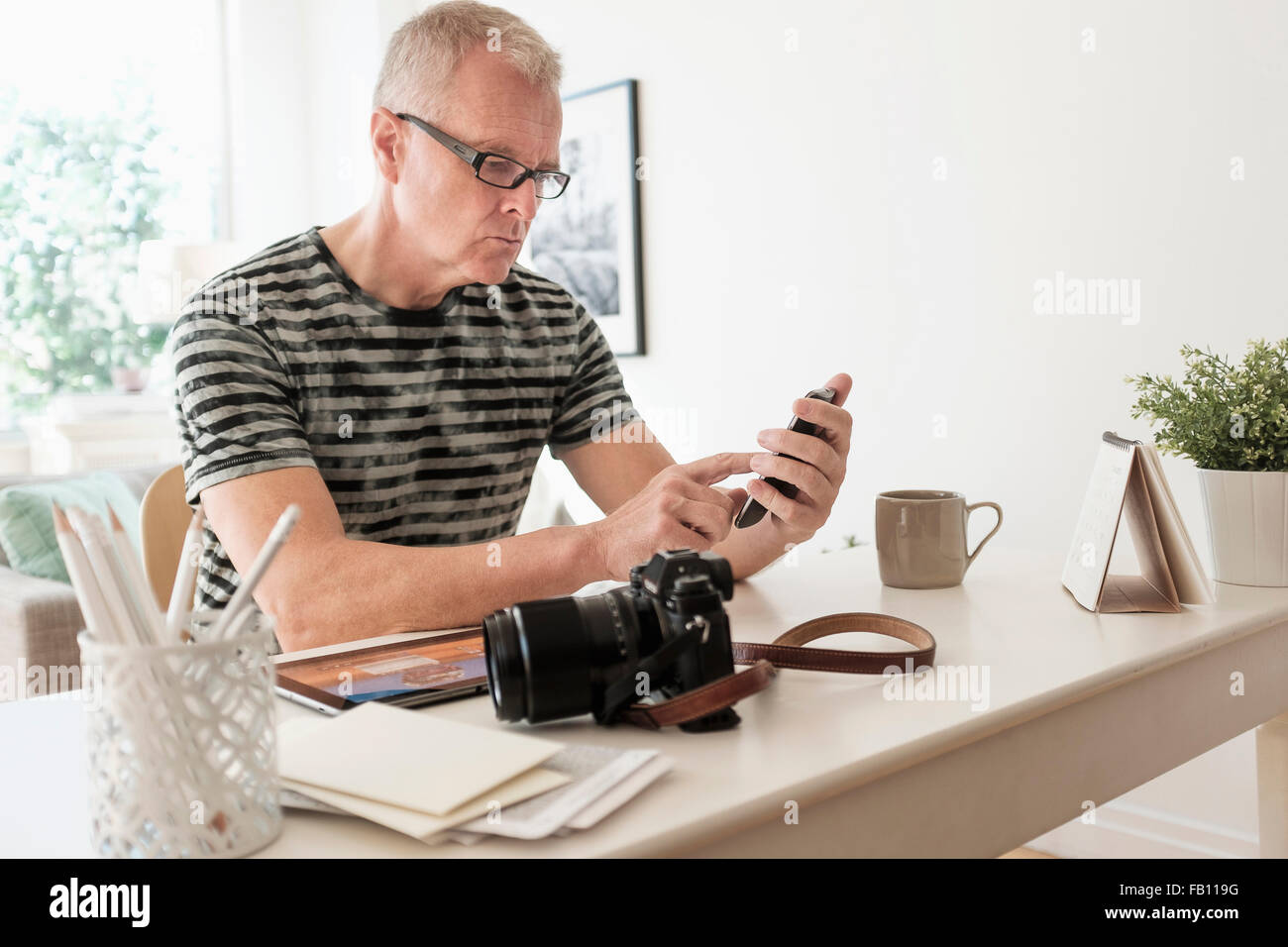 Uomo in ufficio a casa utilizza lo smartphone Foto Stock