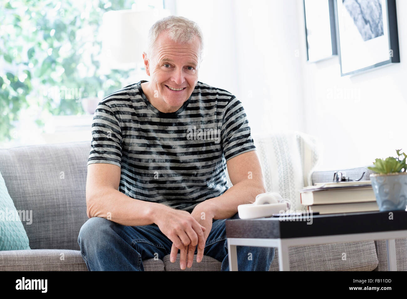 Ritratto di uomo sorridente seduto sul divano di casa Foto Stock