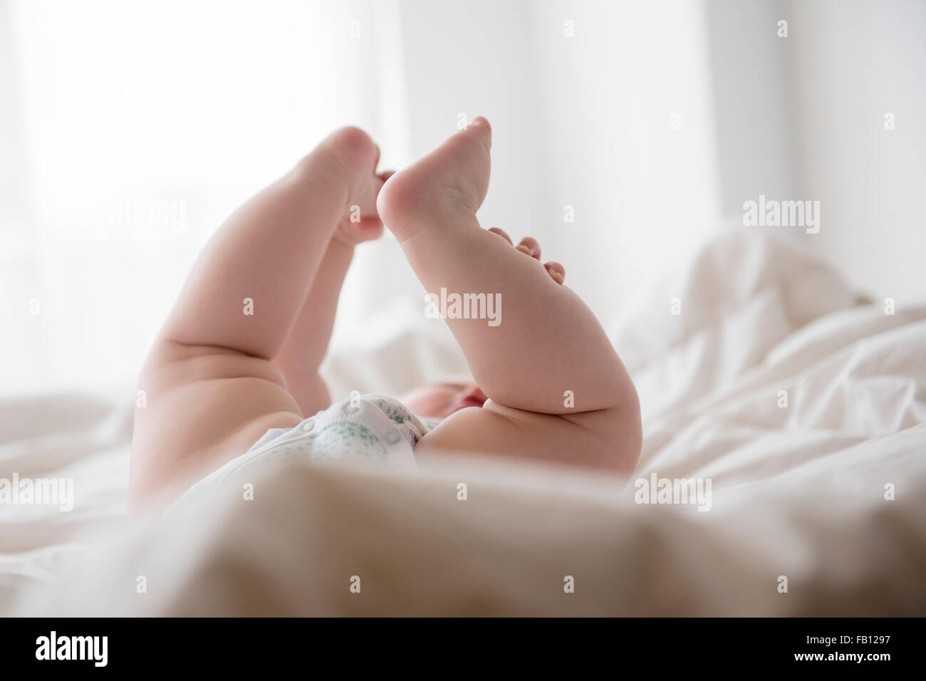 Baby girl (12-17 mesi) disteso con le gambe in alto Foto Stock