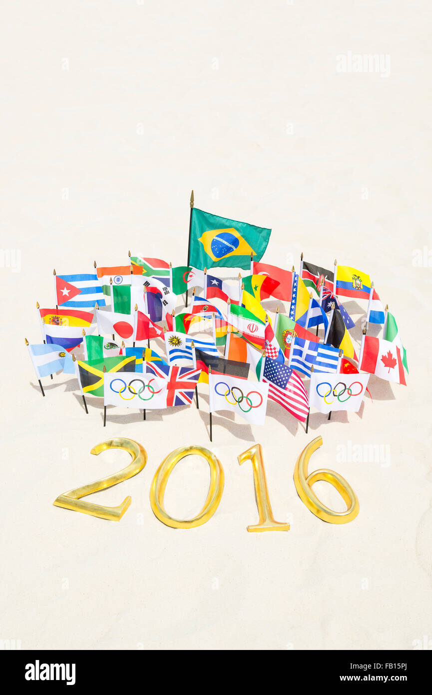 RIO DE JANEIRO, Brasile - 20 Marzo 2015: Golden 2016 segno si siede sulla sabbia con internazionale e bandiere olimpica. Foto Stock